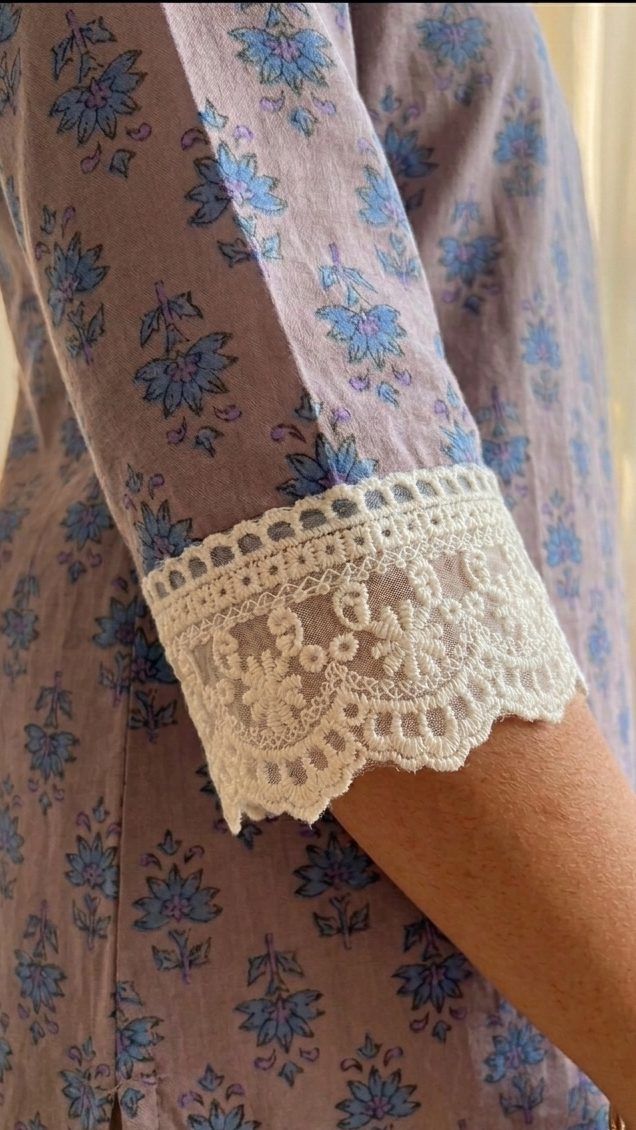 Close-up of a floral dress with lace cuffs and a gold bracelet.