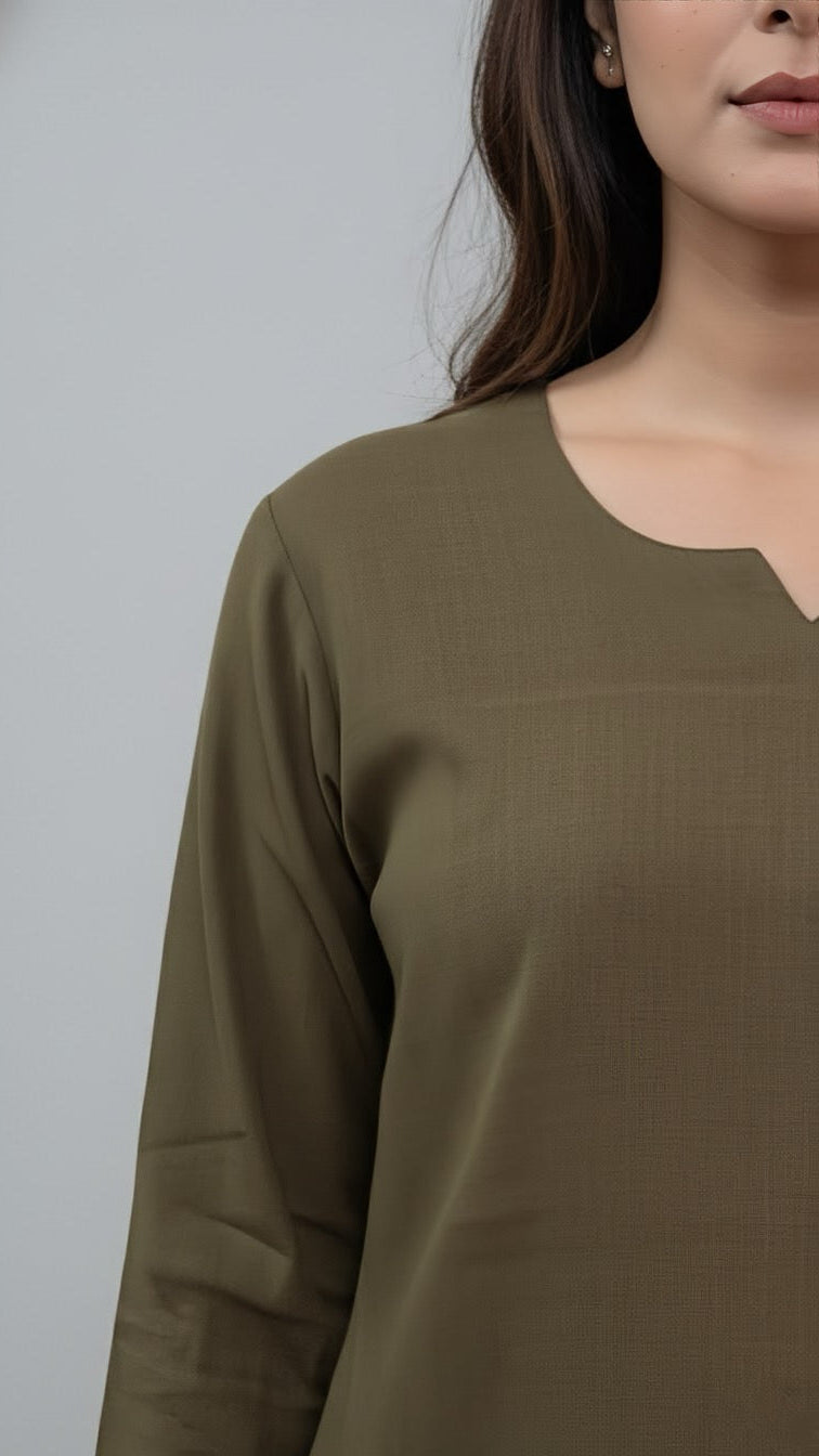 Woman wearing a green long-sleeve top against a gray background