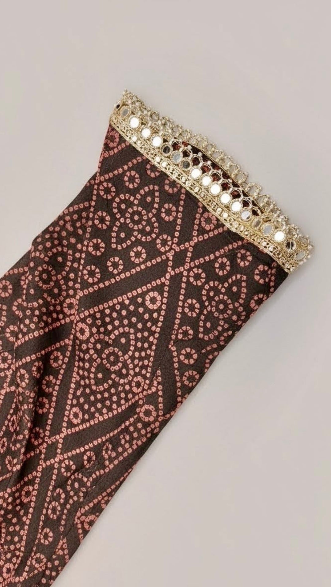 Decorative fabric with intricate pattern and gold trim on a gray background