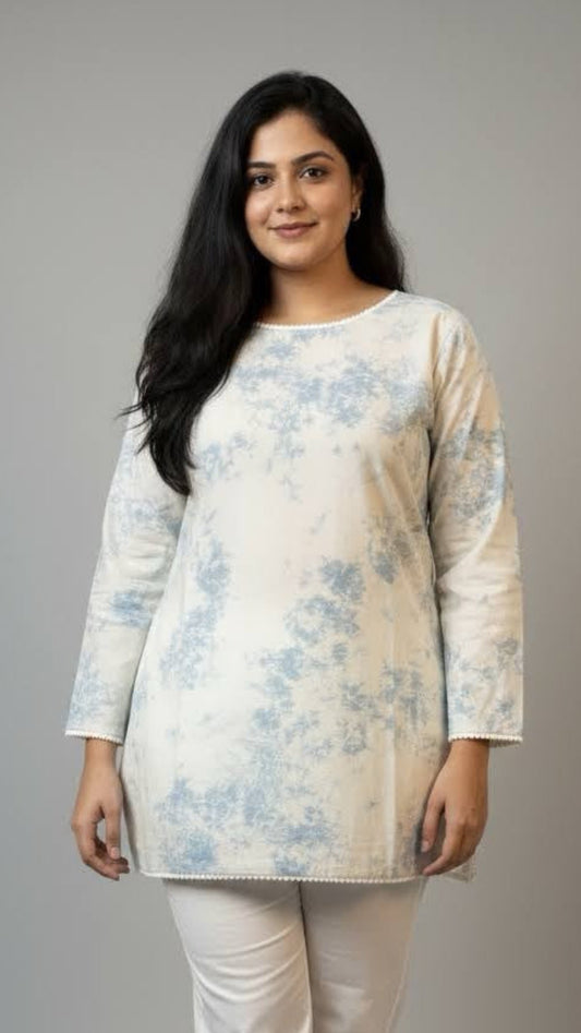 Woman wearing a floral top and white pants on a gray background