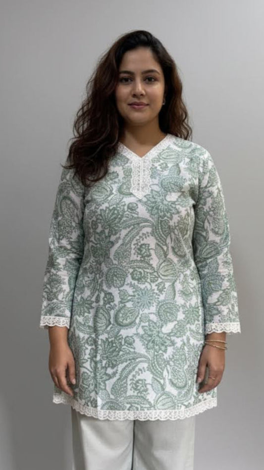 Woman wearing a light green patterned kurta with white pants on a gray background