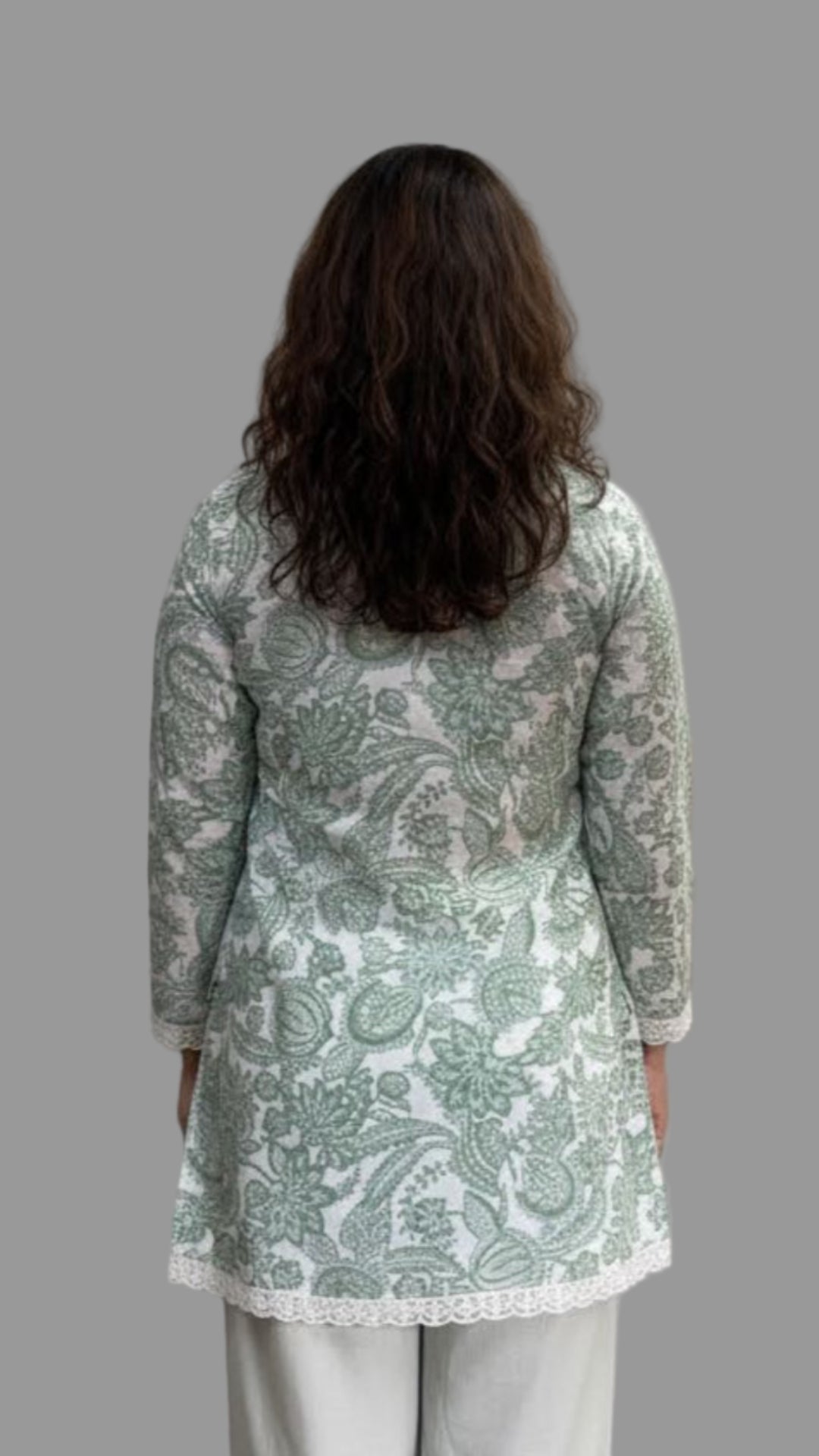 Person wearing a light green and white patterned kurta with white pants on a plain background