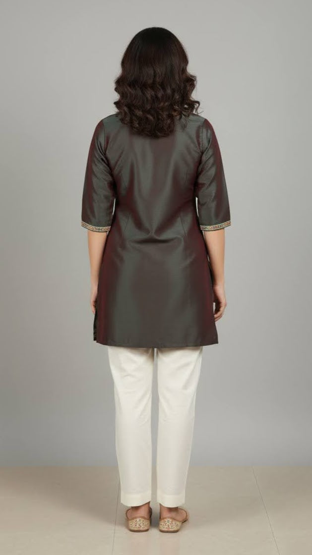 Woman wearing a dark green kurta with white pants against a gray background
