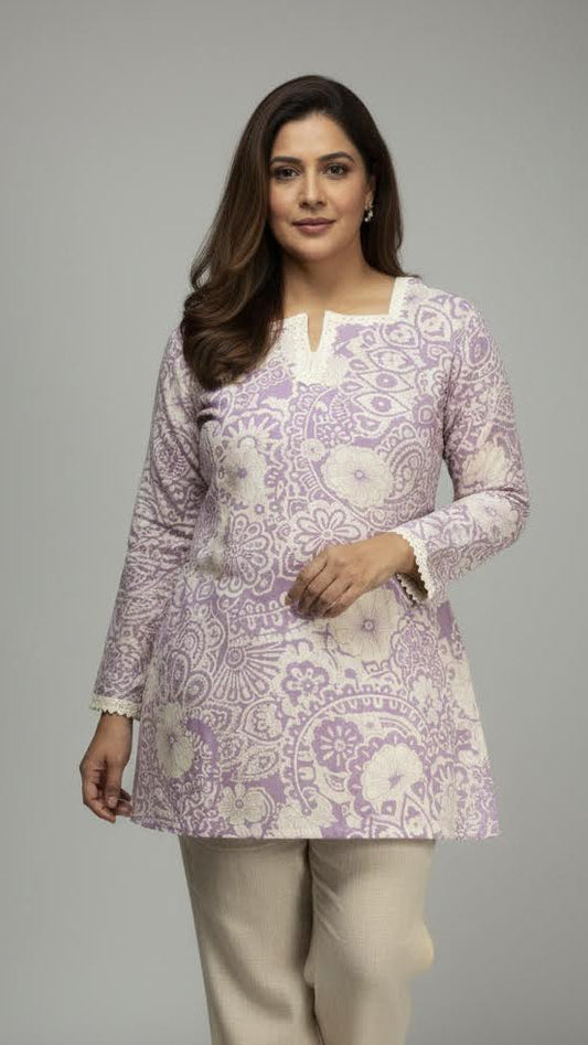 Woman wearing a patterned purple and white top with beige pants on a gray background
