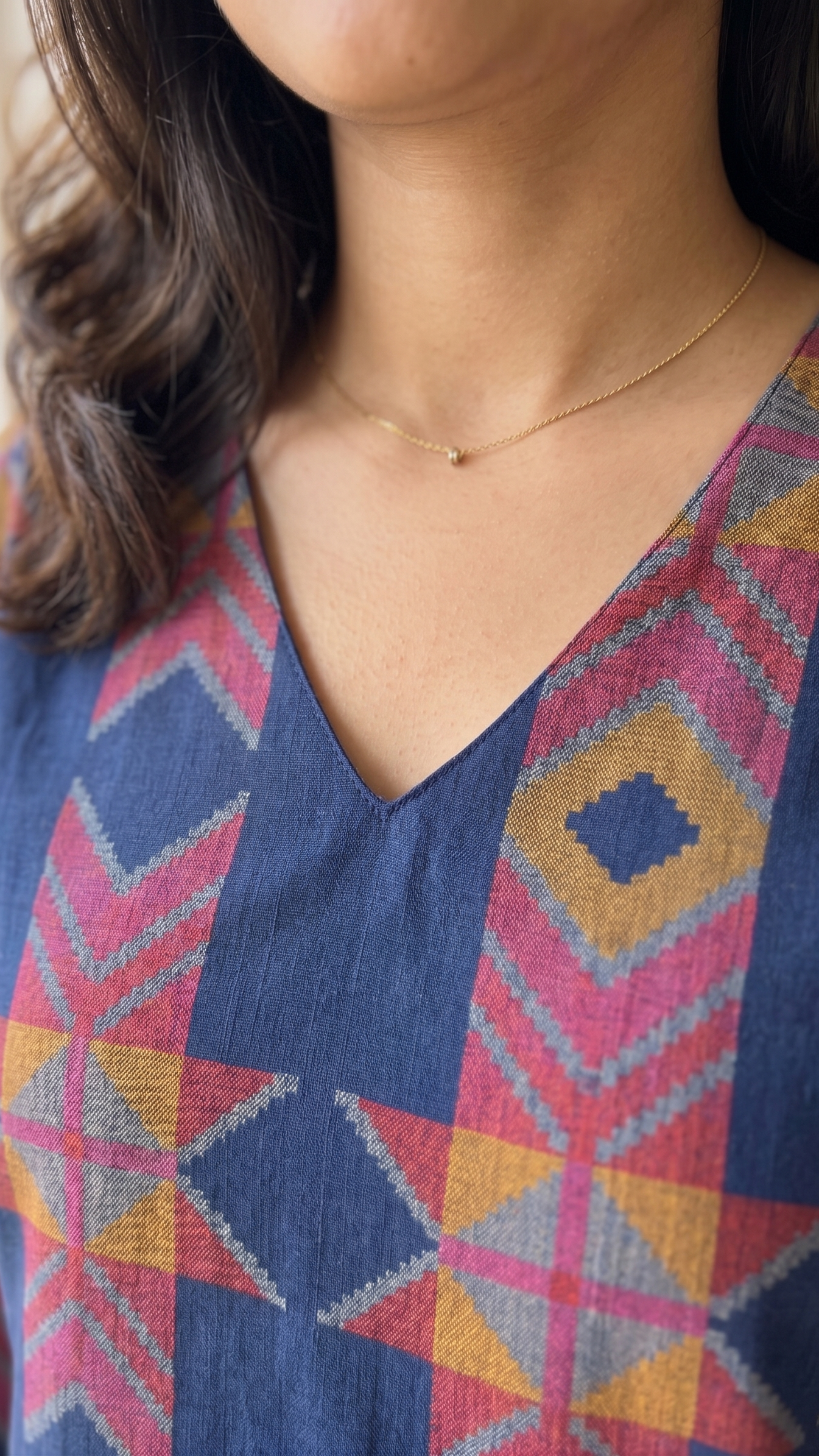 Person wearing a colorful patterned top with a blurred background