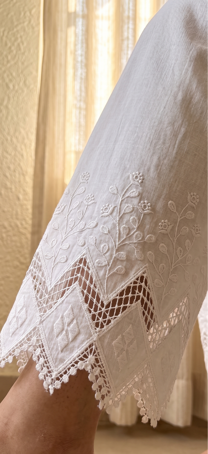 Close-up of a person wearing a white lace garment with a neutral background