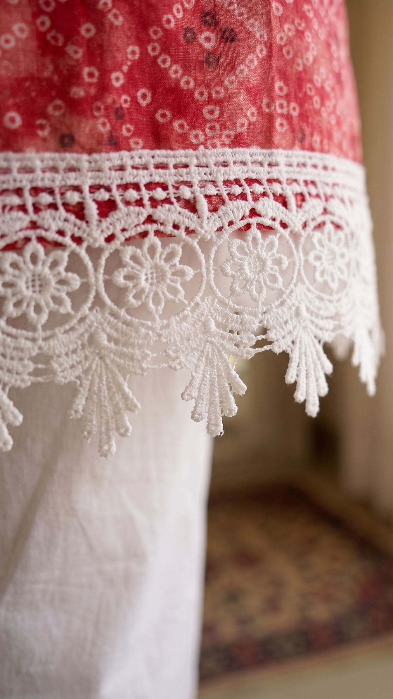 Close-up of a red fabric with white lace trim in an indoor setting.