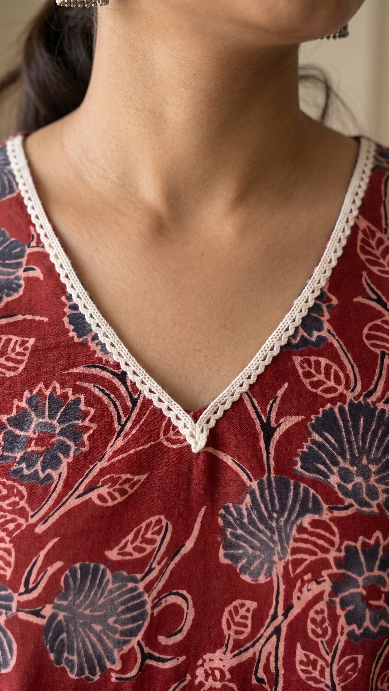 Red floral patterned top with lace trim on a neutral background