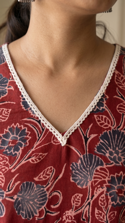 Red floral patterned top with lace trim on a neutral background