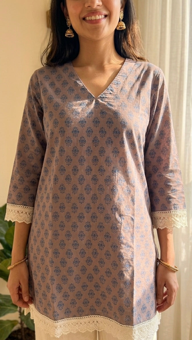 Woman wearing a patterned kurta standing indoors with plants in the background