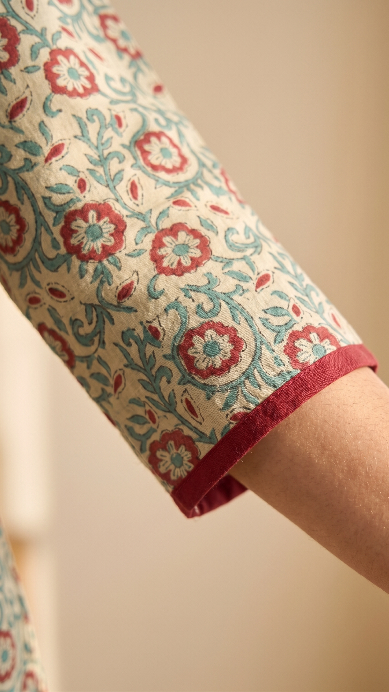 Close-up of a sleeve with floral pattern and red trim on a blurred background