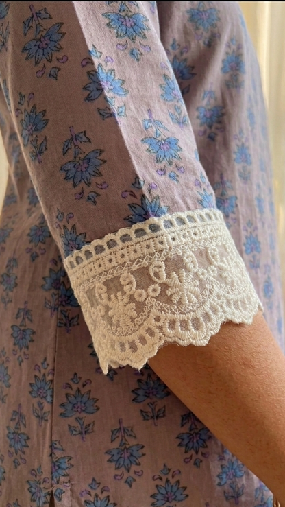 Close-up of a floral dress with lace cuffs and a gold bracelet.