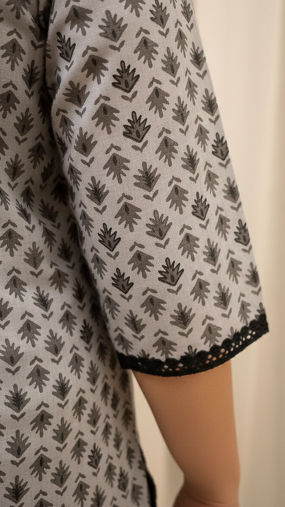 Patterned garment with black leaf design on a neutral background
