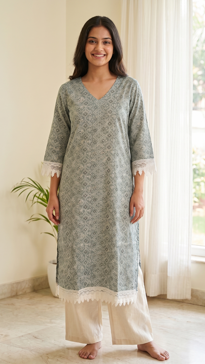 Woman wearing a gray floral kurta with white pants in a bright room.