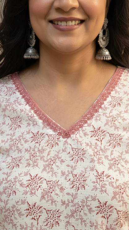 Woman wearing a white floral blouse with red embroidery, smiling.