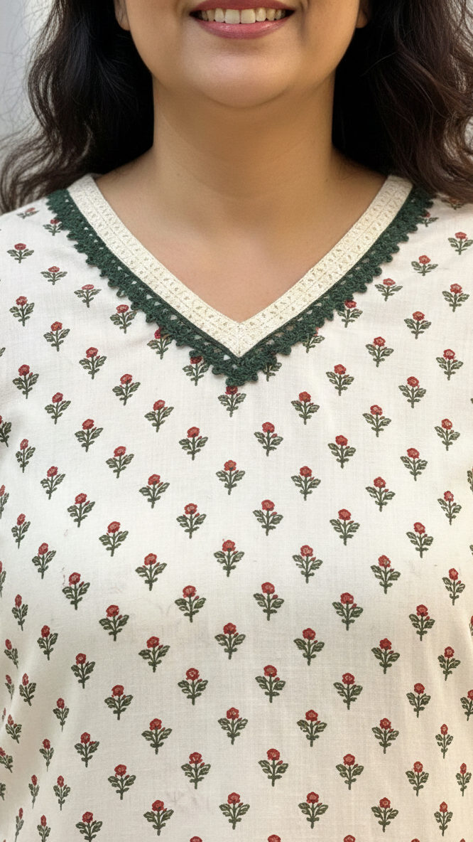 Woman wearing a white top with red floral pattern and green lace trim.
