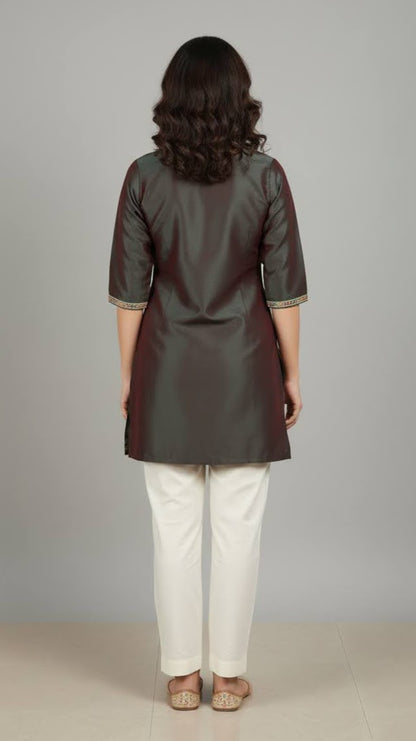 Woman wearing a dark green kurta with white pants against a gray background