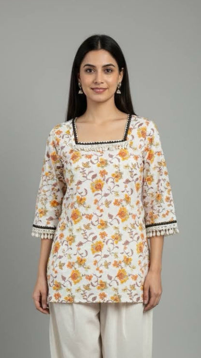 Woman wearing a floral top and white pants on a gray background